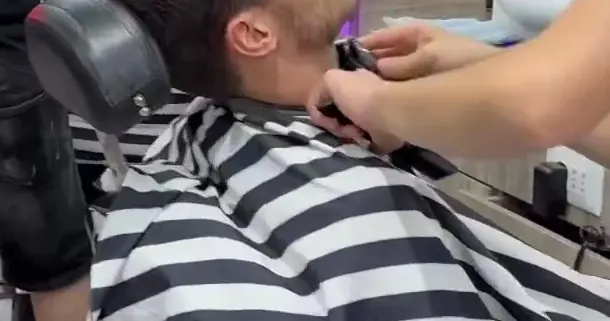 Close-up of a beard trim with the clipper, striped cape