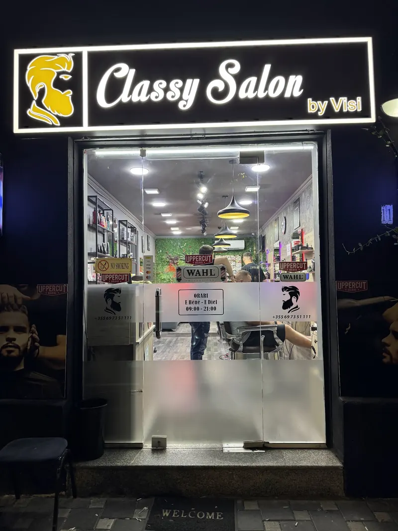 The lit Classy Salon by Visi sign over the door at night