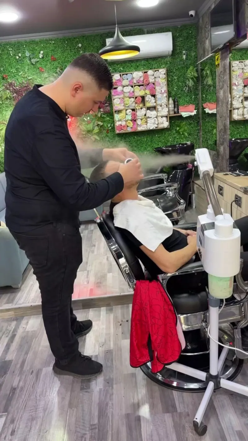 A barber giving a steam face treatment